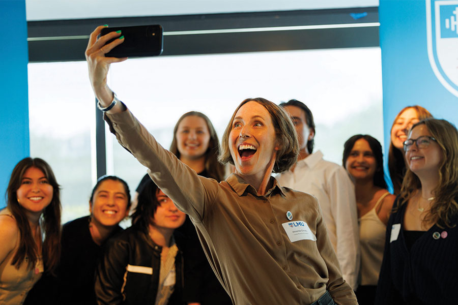 LMU Professor Amanda Christy smiling and taking a selfie with students from her Gender, Race, and Disability class.
