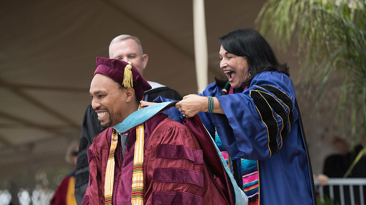 A graduate having a sash draped over them on stage