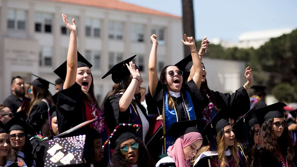Graduates standing up and cheering from their seats during commencement