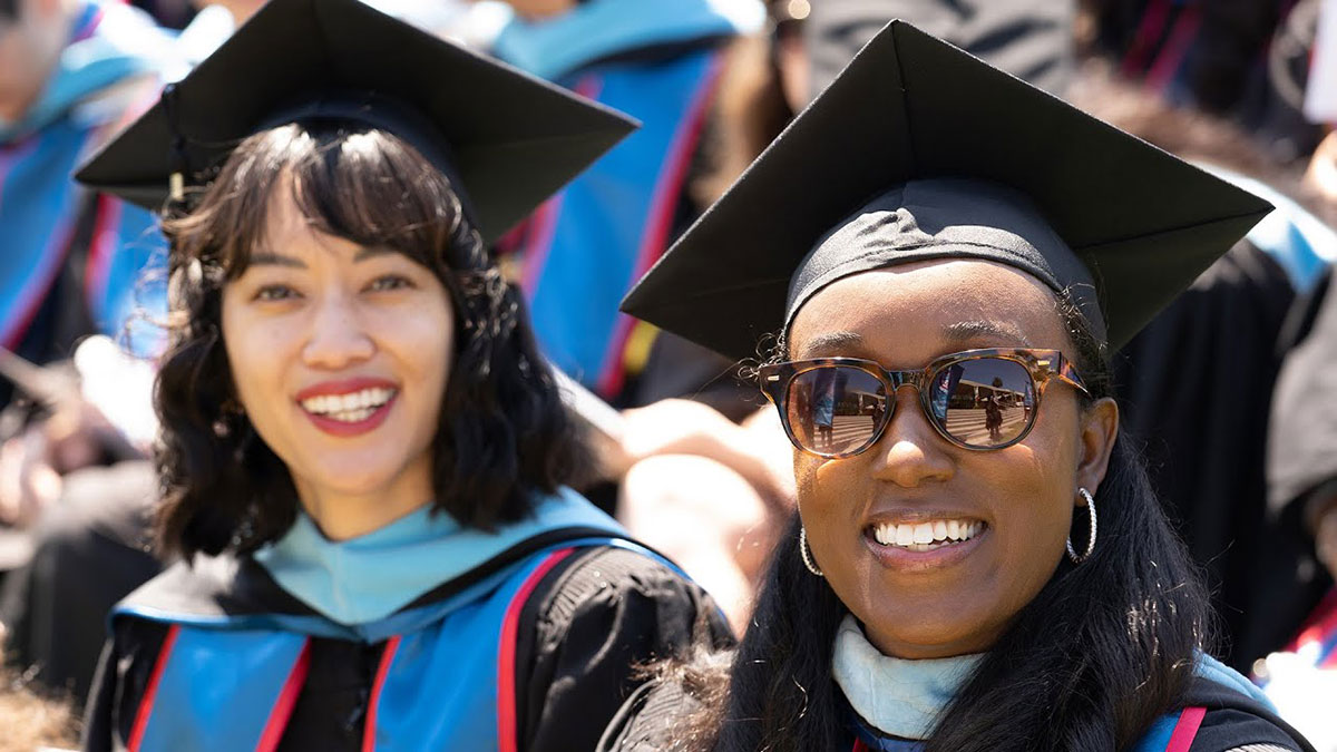 Graduates seated and smiling during commencement
