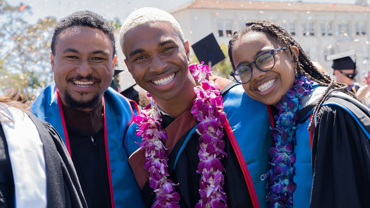 Several students smiling at the camera after having just graduated