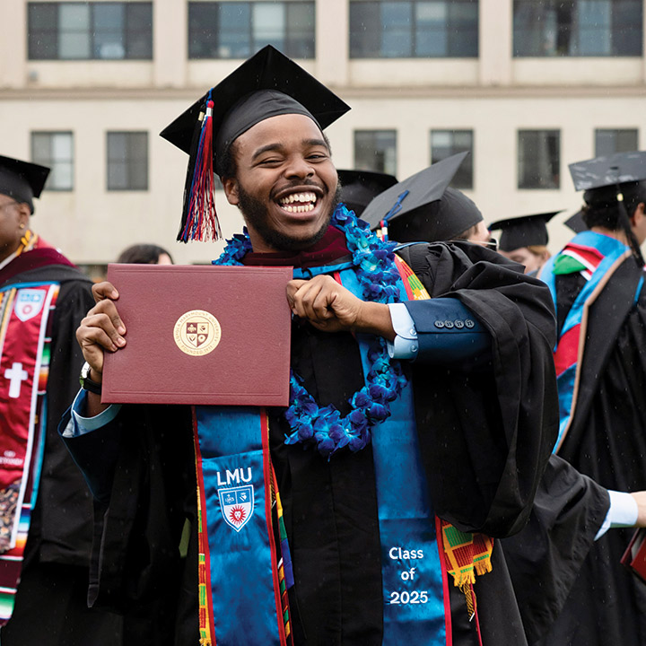 LMU Graduate holding their diploma